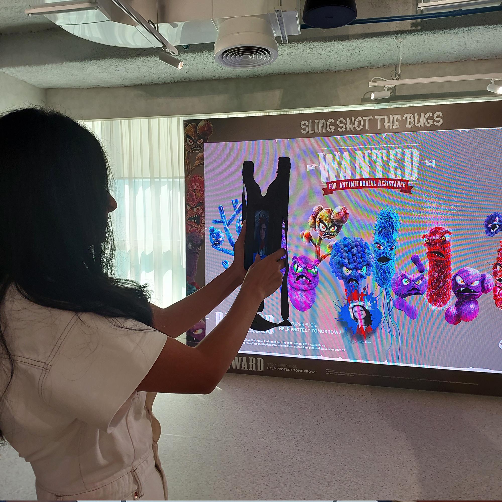 Interactive digital photo booth featuring a slingshot-style camera controller connected to a large LED display for branded event engagement and instant photo experiences.