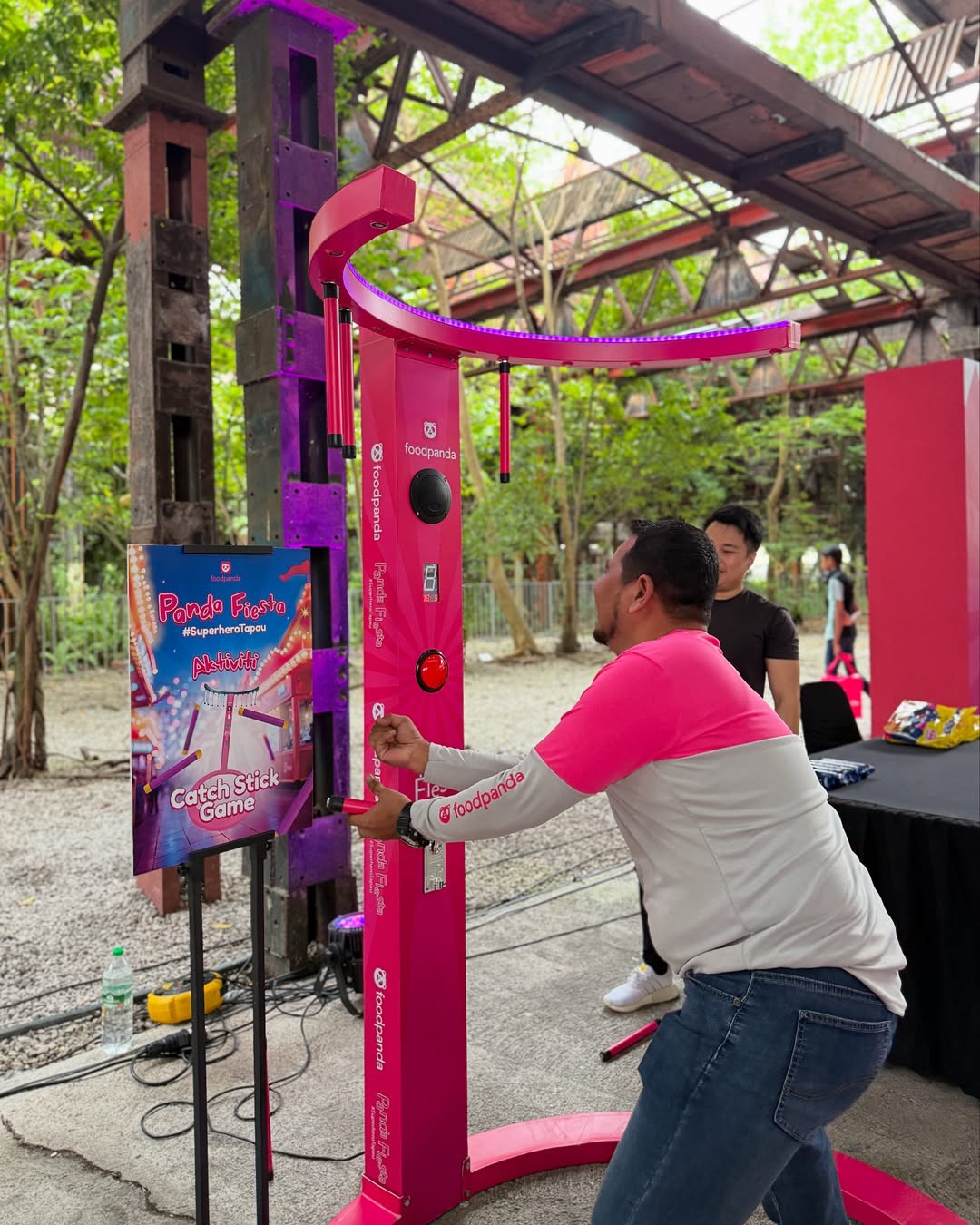 A participant playing the Foodpanda branded Catch Stick Game at a corporate event activation, featuring an interactive reflex challenge installed and managed by Fabx Events, an event management and equipment rental company.