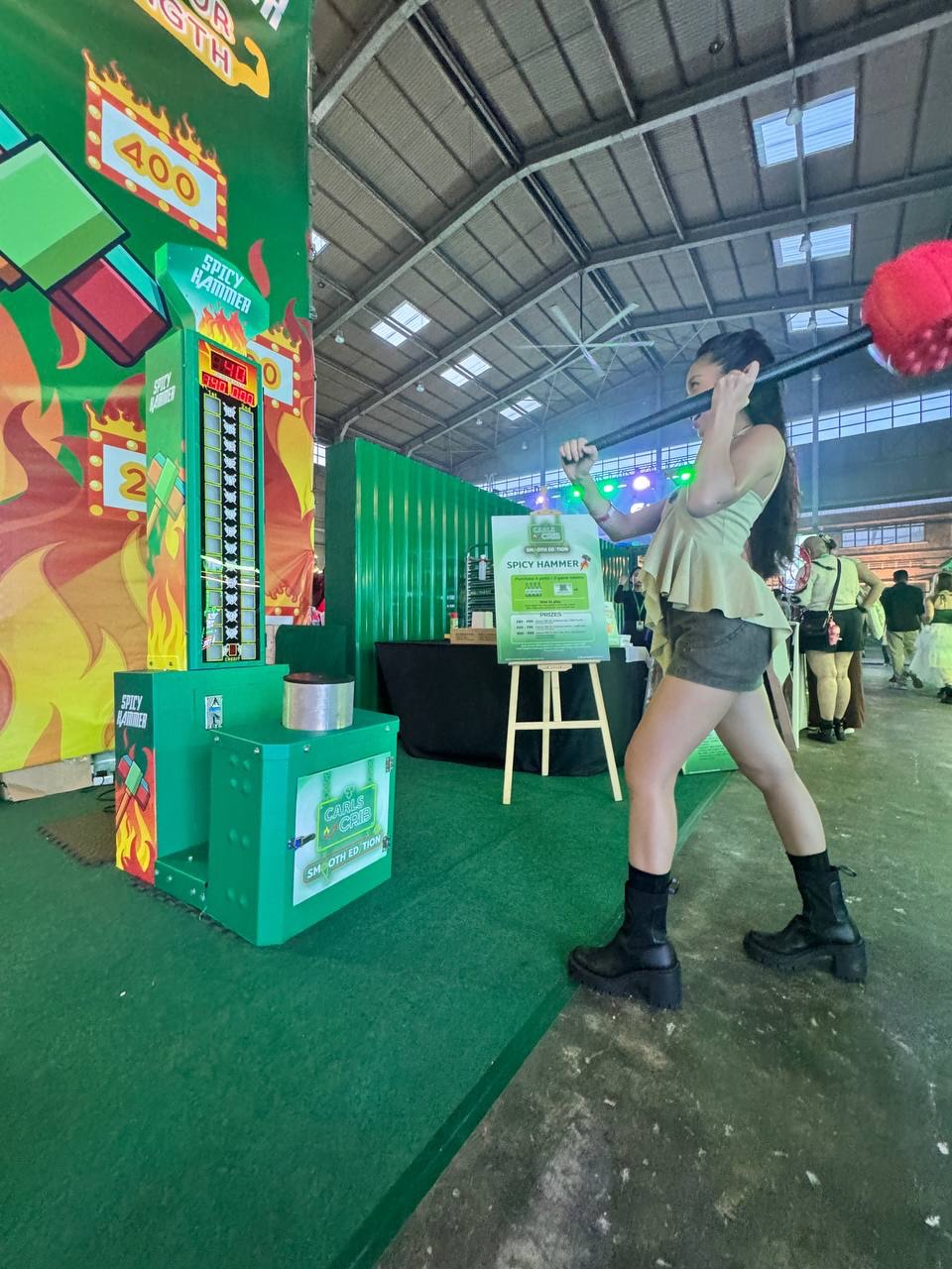 Participant using hammer to test strength on high striker game at party or carnival