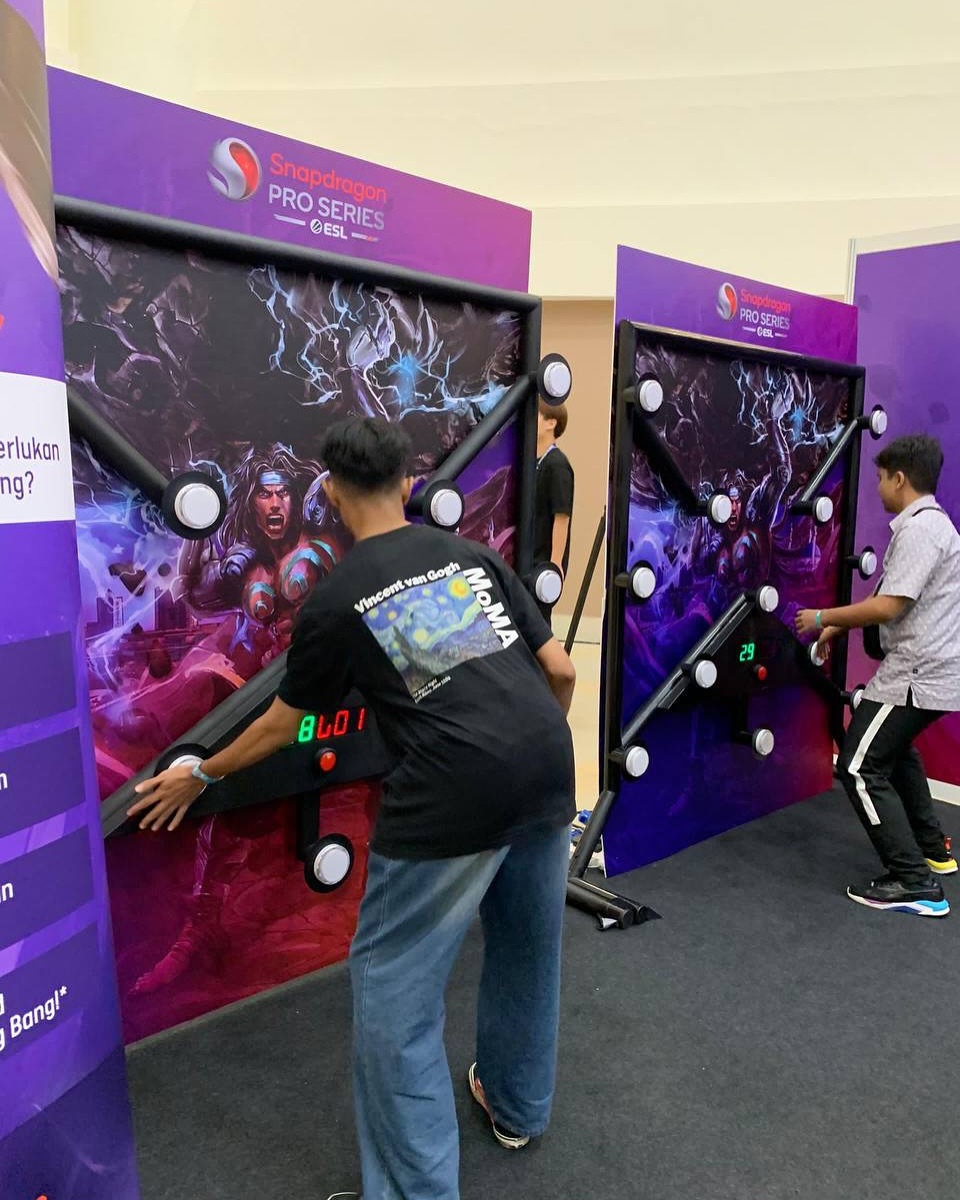 Participants playing a custom-branded Batak Reaction Challenge game at a promotional event, testing speed, reflexes, and hand-eye coordination through illuminated touch targets.